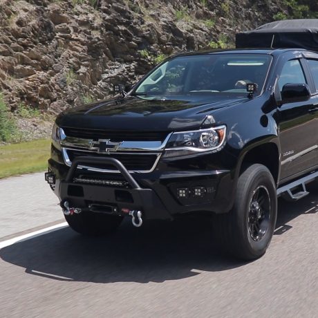 Black chevy truck driving the highway with aftermarket accessories